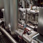 Insulated pipes and pressure gauges in an industrial plant.